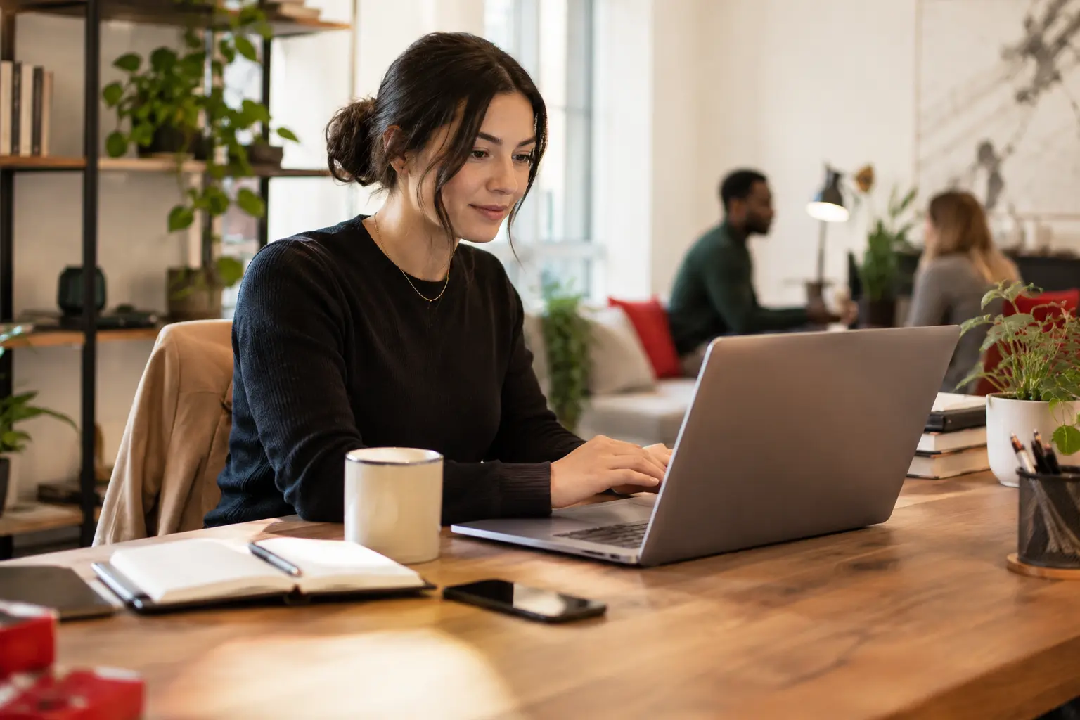 An office administrator triaging customer messages at a laptop in a welcoming shared office, no readable text on screen.